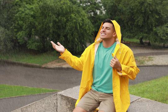 Man with raincoat walking under rain in park