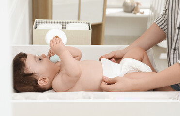 Mother changing baby's diaper on table at home, closeup