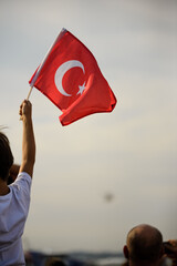 A boy holding a Turkish flag and police helicopters demonstrating in the sky on the liberty day of Izmir.