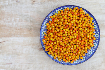 A plate of ripe sea buckthorn in a beautiful plate. Copy space