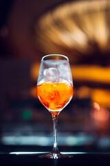 Glass of orange cocktail at bar counter background.