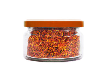 Dried saffron in a transparent glass jar. Close-up. Isolated on white background. Condiments and spices.