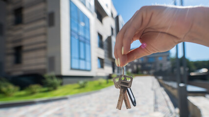 A woman holds the keys to a new house. Close-up of a female hand. Buying a property.