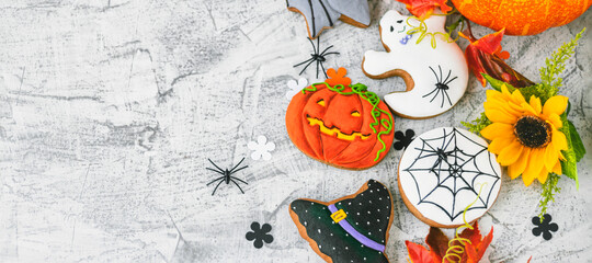 banner with Halloween background with cookies, leaves, sunflower and spiders, top view. Halloween objects on textured concrete with space for text. Vintage background Halloween celebration. Flat lay.