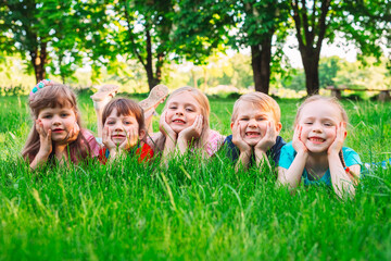 A group of children lying on the green grass in the Park. The interaction of the children.