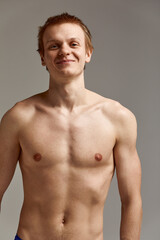 Fototapeta premium Young swimmer in excellent physical shape, on a gray background with copy space, call for sports, advertising banner