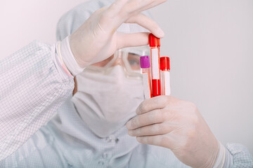 doctor man in flu mask and protective gloves holding a test tube with a coronavirus blood sample....
