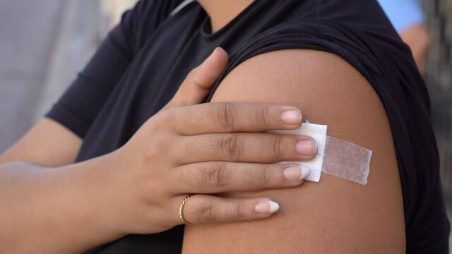 Detail of Latina girl touching the arm in pain where she has recieved the covid vaccine 
