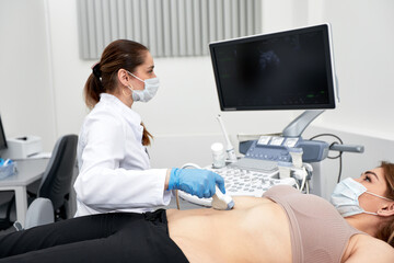 Female doctor gives the patient a female abdominal ultrasound. Ultrasound scanner in the hands of a...