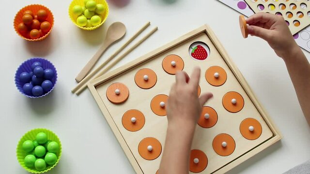 A child playing a children's educational game for the development of memory. It is necessary to find two of the same pictures. The concept of kids leisure and preschool education.