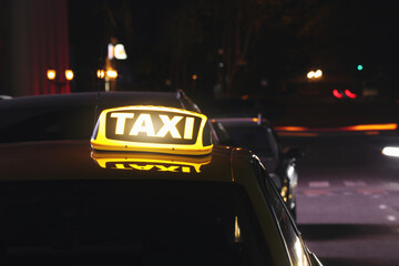 Fototapeta na wymiar Taxi car with yellow sign on city street at night