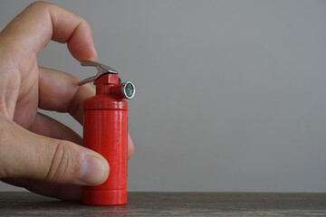 miniature fire extinguisher and man's hand - obrazy, fototapety, plakaty