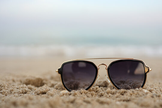 Beautiful background of Turquoise Sea with sunglasses lying on the sand beach. The concept of Rest Vacation. Wide Horizontal Colorful Wallpaper with selective focus and copy space