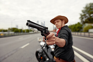 Obraz premium mafia man on bike with handgun. Sporty biker handsome rider male. Chase