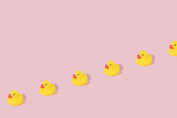 Creative pattern made with yellow rubber duck  on pastel pink background. Surreal bathing concept. Retro style aesthetic idea with copy space.