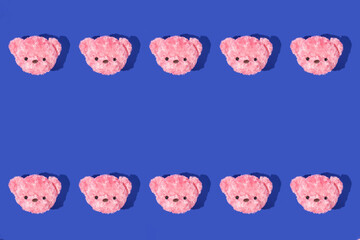 Creative pattern with pastel pink teddy bear heads on deep blue background. Aesthetic fashion concept with toy. Bold colors trendy idea. Minimal copy space.
