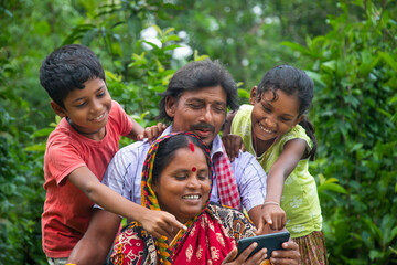 Indian Rural Parents and their two children watching movie in agricultural field