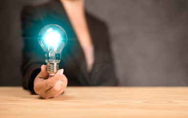 Idea concept. businesswoman holds a glowing blue light bulb. Woman hand holding light bulb on...
