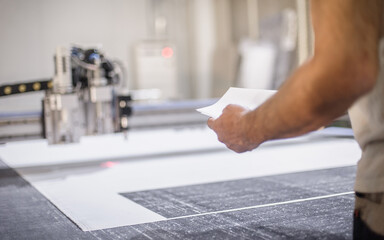 Technician works on CNC digital cutter machine for cutting textile