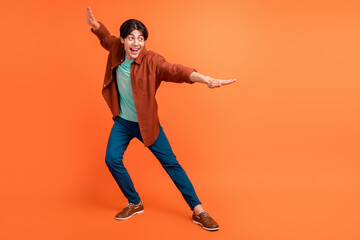 Full size photo of cheerful smiling handsome man dancing fooling around isolated on orange color background