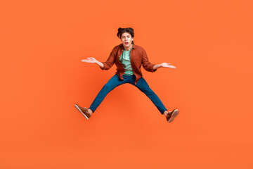 Fototapeta na wymiar Full size photo of unhappy upset man jumping shrug shoulders wtf hesitant doubt isolated on orange color background