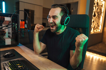 Happy young man gamer streamer in headphones - obrazy, fototapety, plakaty