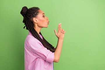 Photo of sweet confident dark skin lady wear pink shirt blow fume handgun empty space isolated green color background