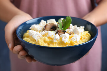 Woman holding bowl of banosh with brynza and mushrooms, closeup. Traditional Ukrainian dish