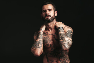 Portrait of handsome confident stylish hipster lambersexual model. Sexy modern man. Naked torso with tattoos.Fashion male posing in studio on dark background - obrazy, fototapety, plakaty