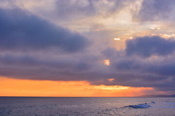 Purple clouds and orange sunset or sunrise over the sea. - 458232997