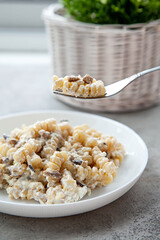 Delicious dish fusilli pasta with creamy mushroom sauce on a gray stone table