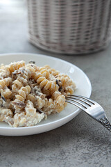 Delicious dish fusilli pasta with creamy mushroom sauce on a gray stone table