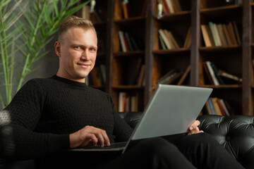 man sitting on a comfortable sofa with a laptop 