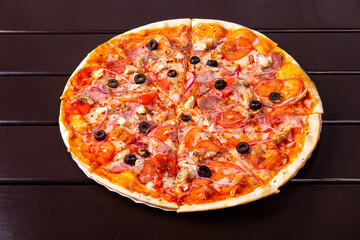 A whole rustic pizza with fried chicken, bacon, onion and tomatoes