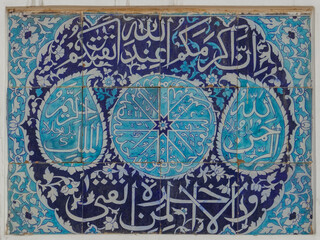 Beautiful ancient blue and white ceramic tile panel with religious arabic calligraphy on wall of...