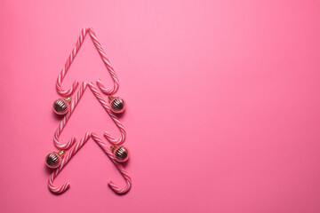 Christmas tree figure made of sweets and decorative balls on a pink background, top view. Christmas and New Year concept
