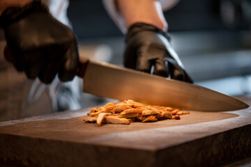 Cooking juicy beef steak by chef hands on dark black background with copy space for text menu or recipe.