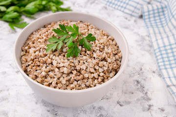Freshly cooked buckwheat porridge in a plate on a gray background.