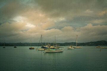 Evening clouds reflected in calm waters of a small harbour. Fishing and sailing boats anchored close to the shore