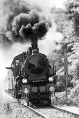 Steam train runs on the tracks in the countryside. Black and white photography. - 458234994