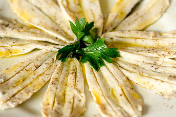 Marinated anchovies with vinegar, olive oil, pepper and parsley, in a plate, close up