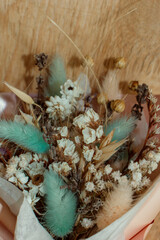 A bouquet of delicate beautiful dried flowers in a pink package. Blue, pink, purple, yellow, white
