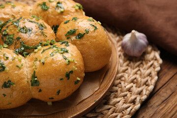 Traditional pampushka buns with garlic and herbs on wooden table, closeup