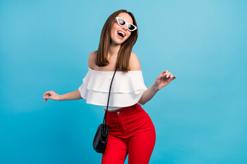 Photo of sweet charming young woman dressed white blouse dark glasses dancing laughing smiling isolated blue color background