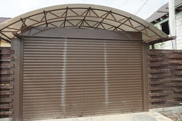 garage facade with brown gates and part of a wooden fence on the street