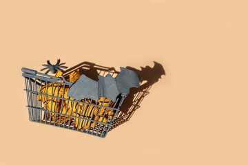 Halloween, festive background beige with hard light shadows. Basket with spiders and bats. Creative halloween.