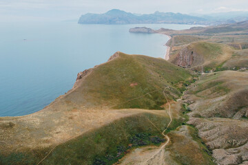 green mountains along the sea coast. in the distance the sharp tops of the mountains. beautiful natural background. beautiful mesmerizing nature