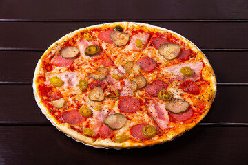 A whole rustic pizza with brisket, red onion, gherkins, salami, mozzarella cheese, jalapeno pepper