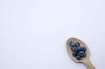 Flat lay of recycled spoon and juicy, fresh blueberries on color table. Space for text. Isolated ripe sweet bilberry fruits in eco spoon on white background. Copy Space. Healthy raw vegetarian food 