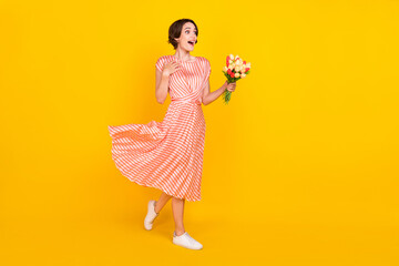Profile photo of cheerful excited girl hold bunch flowers wear striped dress isolated yellow color...
